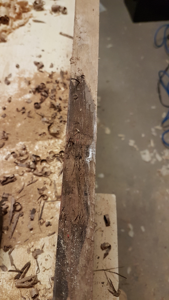 removing bark from the live edge. The process is half finished, with the top showing the bark removed, and the bark still attached at the bottom.
